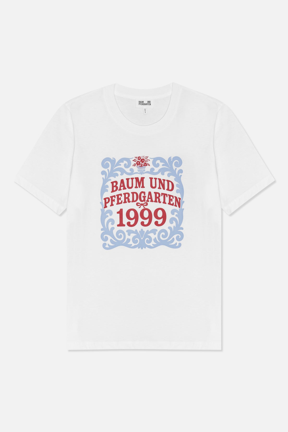 Vorderansicht eines weißen kurzärmeligen T-Shirts mit blauem ornamentalen Rahmen, rotem floralen Detail und dem Schriftzug „Baum und Pferdgarten 1999“.