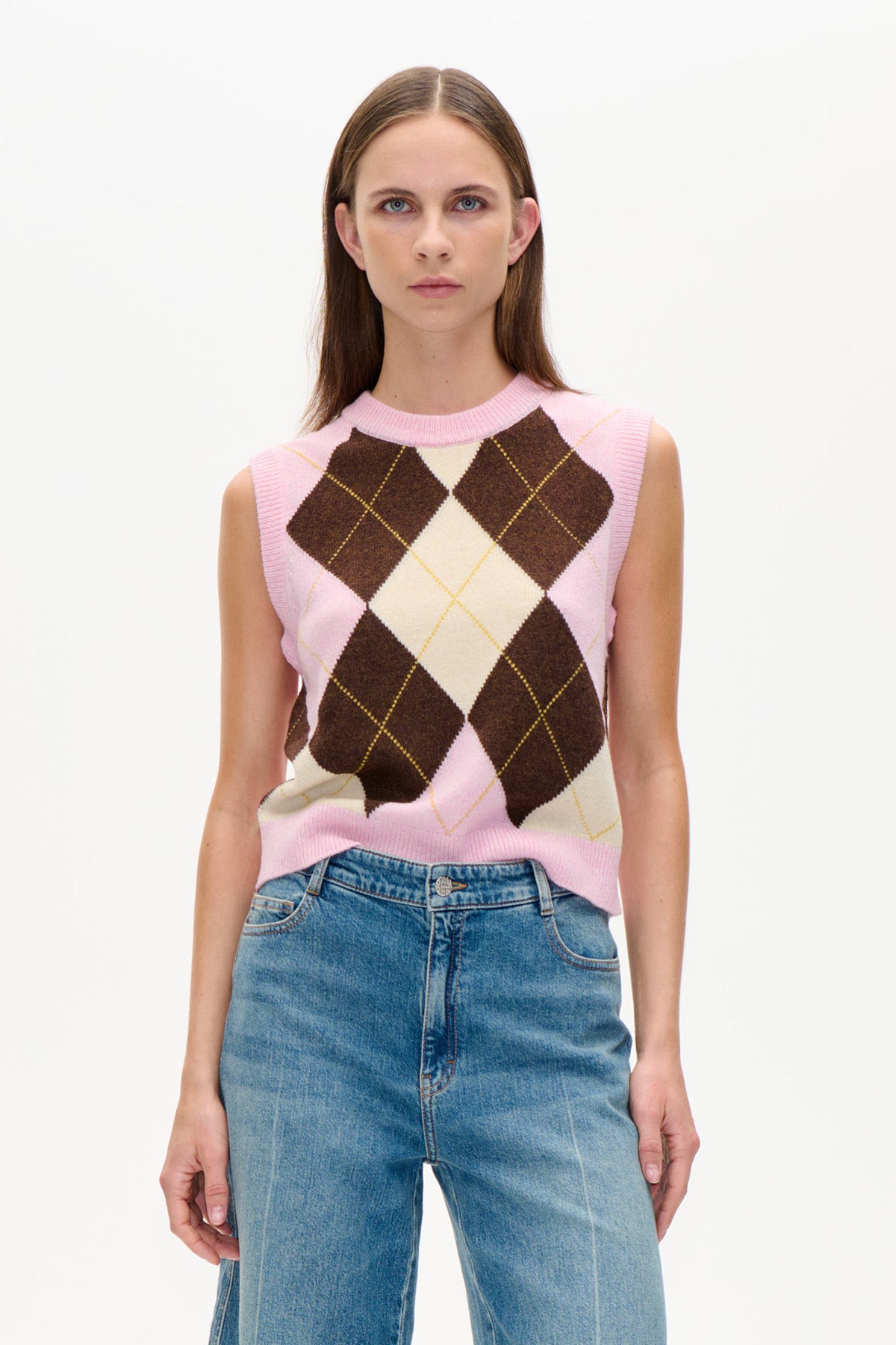 Vorderansicht einer pinken ärmellosen Strickweste mit creme- und dunkelbraunen Argyle-Rauten, getragen zu blauen Jeans.