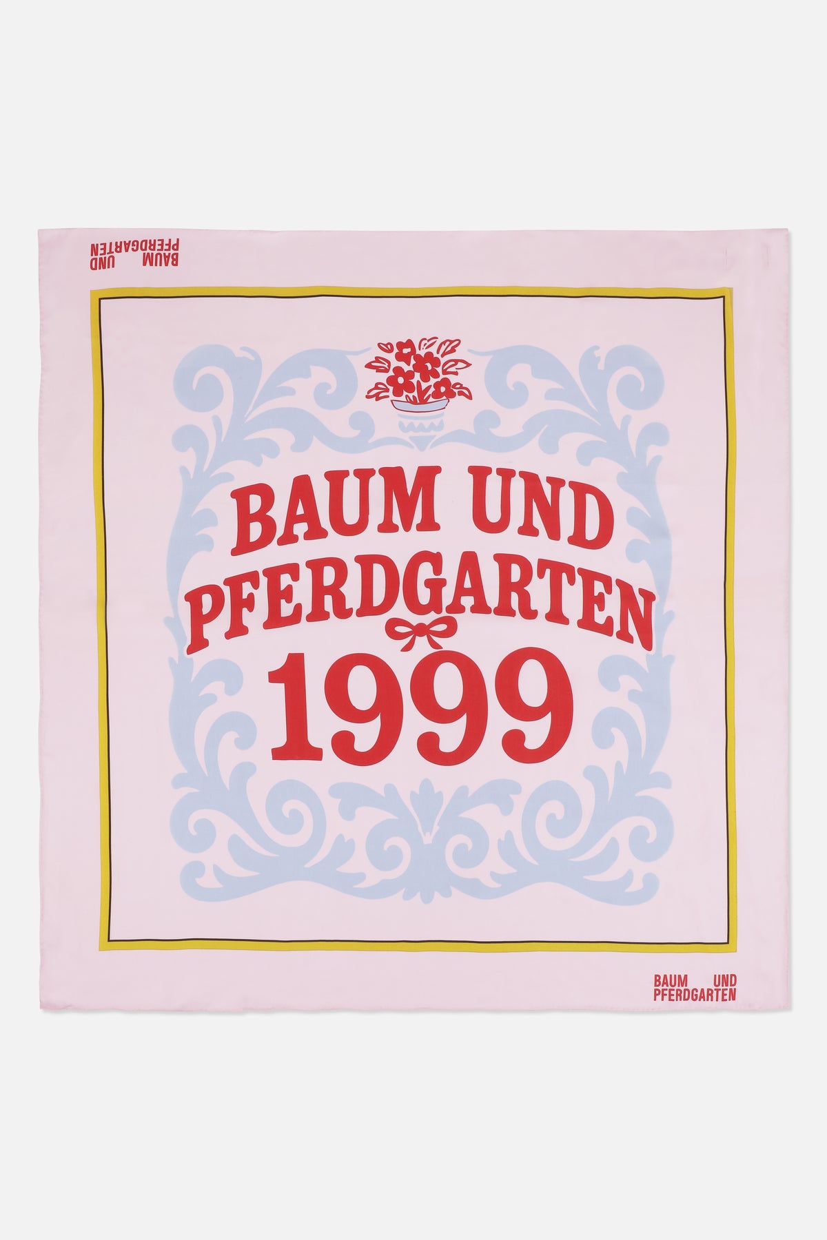 Quadratisches Tuch in blassrosa mit blauem ornamentalen Rankenmuster, gelbem Rand und rotem Schriftzug Baum und Pferdgarten 1999
