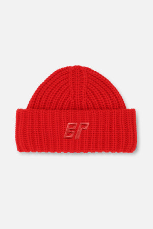 Nahaufnahme einer roten, grob gestrickten Mütze mit umgeschlagenem Bund und ton-in-ton besticktem BP-Monogramm.
