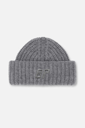 Grauer, grob gestrickter Beanie mit umgeschlagenem Bündchen und besticktem Monogramm, von vorne.