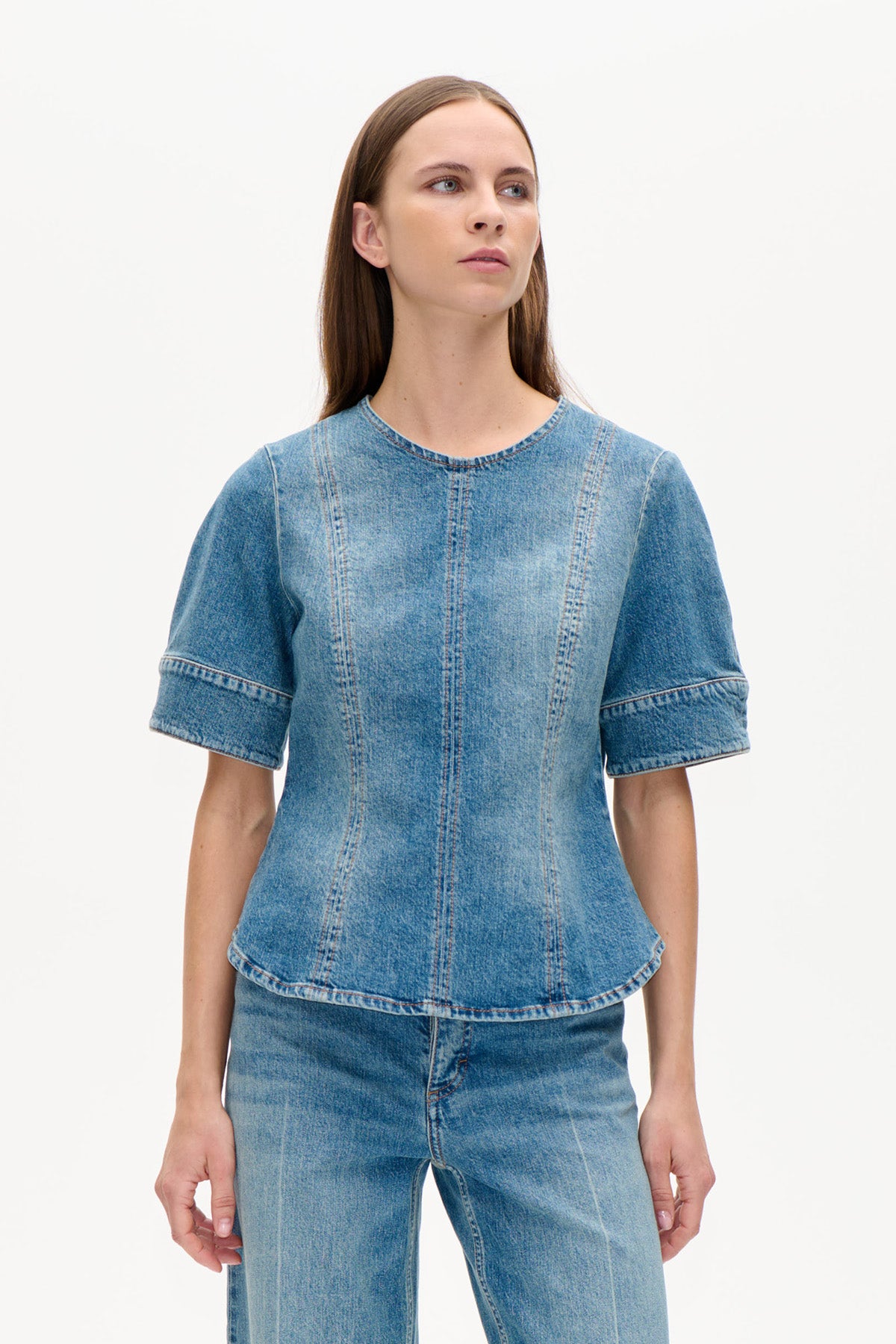 Vorderansicht eines blauen denim-Tops mit rundem Ausschnitt, kurzen weiten Ärmeln und vertikalen Teilungsnähten, getragen zu Jeans.
