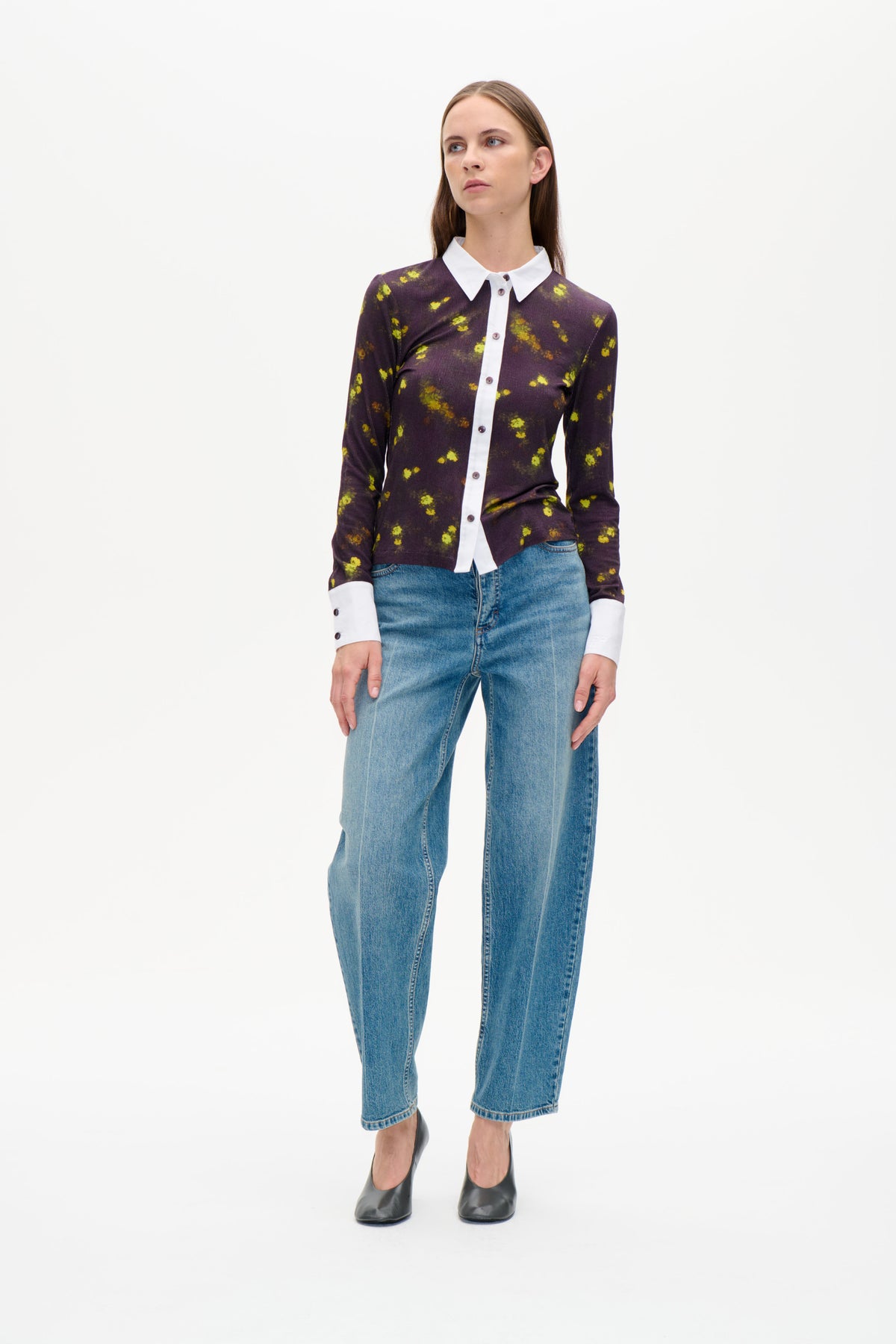 Vorderansicht eines dunkelpflaumenfarbenen Hemds mit Knopfleiste, gelbem Blumenprint, weißem Kragen und Manschetten, gestylt mit blauen Jeans.