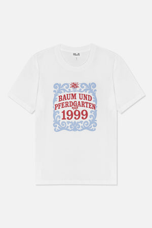 Vorderansicht eines weißen kurzärmeligen T-Shirts mit blauem ornamentalen Rahmen, rotem floralen Detail und dem Schriftzug „Baum und Pferdgarten 1999“.